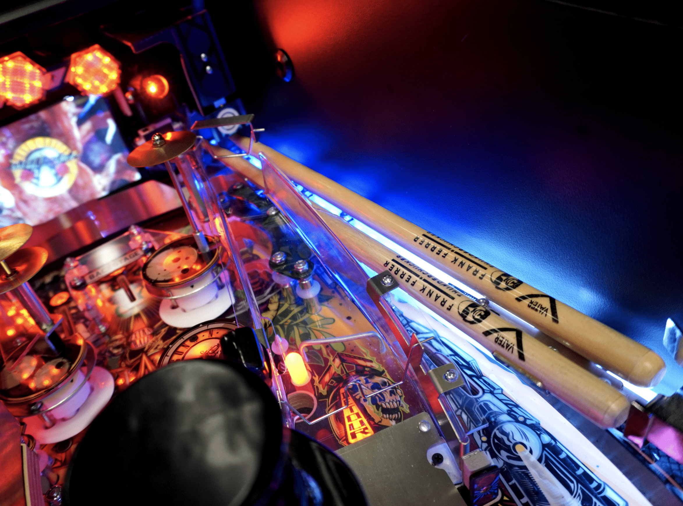 Pinball machine with colorful lights, detailed playfield, and drumsticks