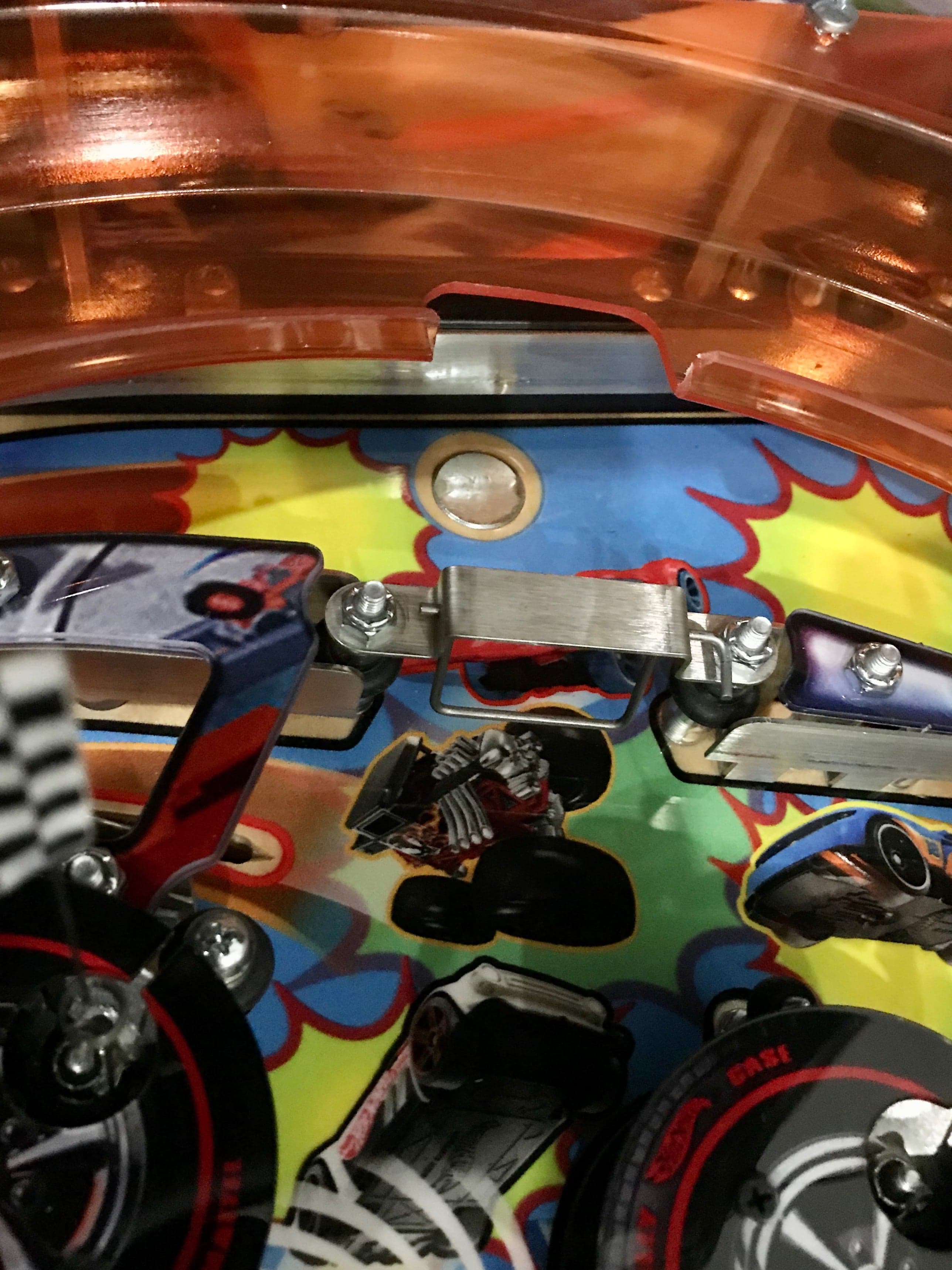 Close-up of a colorful pinball machine interior with mechanical parts