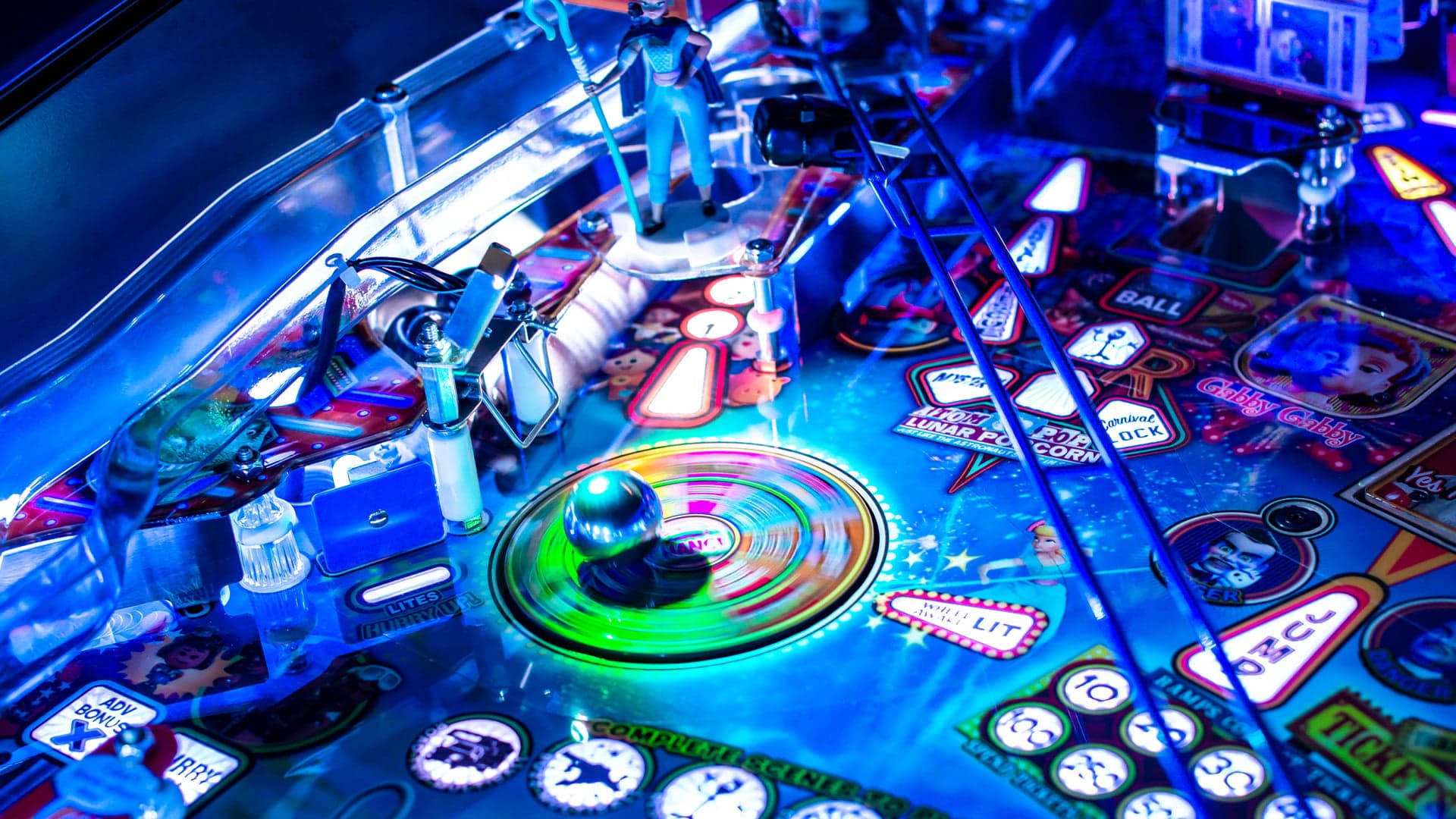 Colorful pinball machine with glowing ball and vibrant blue lighting