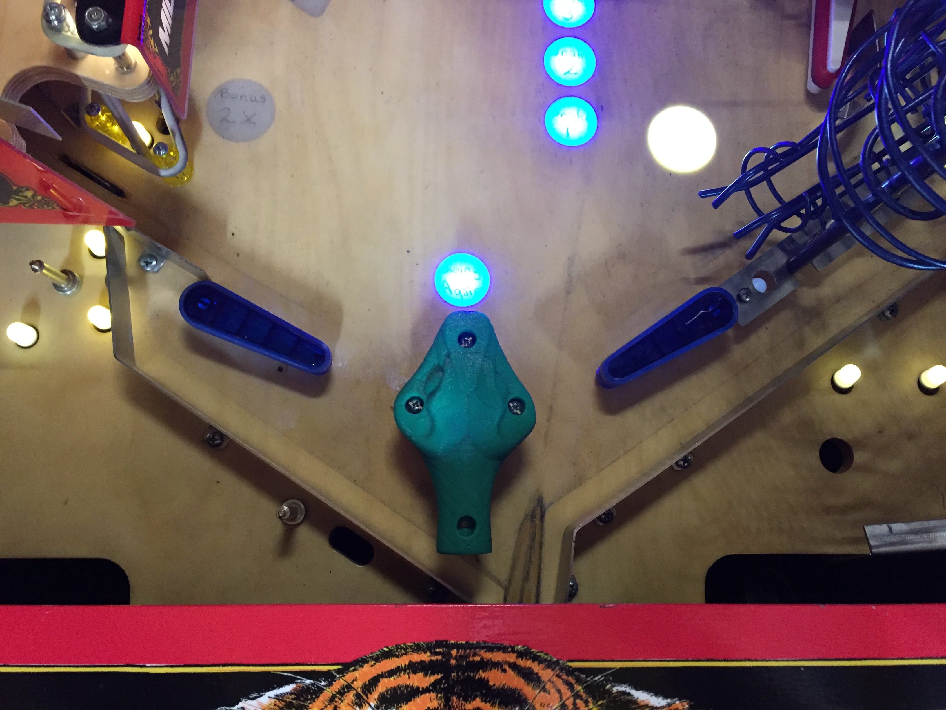Pinball machine detail with blue and white illuminated bumpers