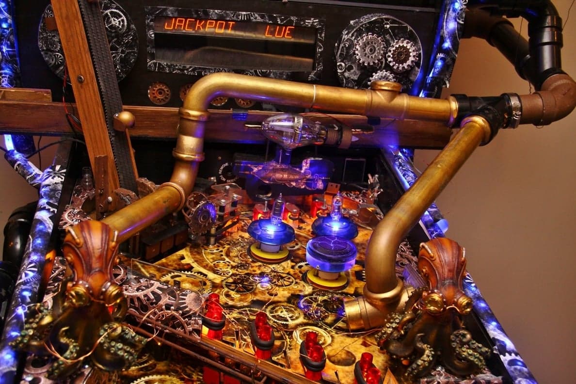 Steampunk pinball machine with golden pipes, gears, and blue-lit components